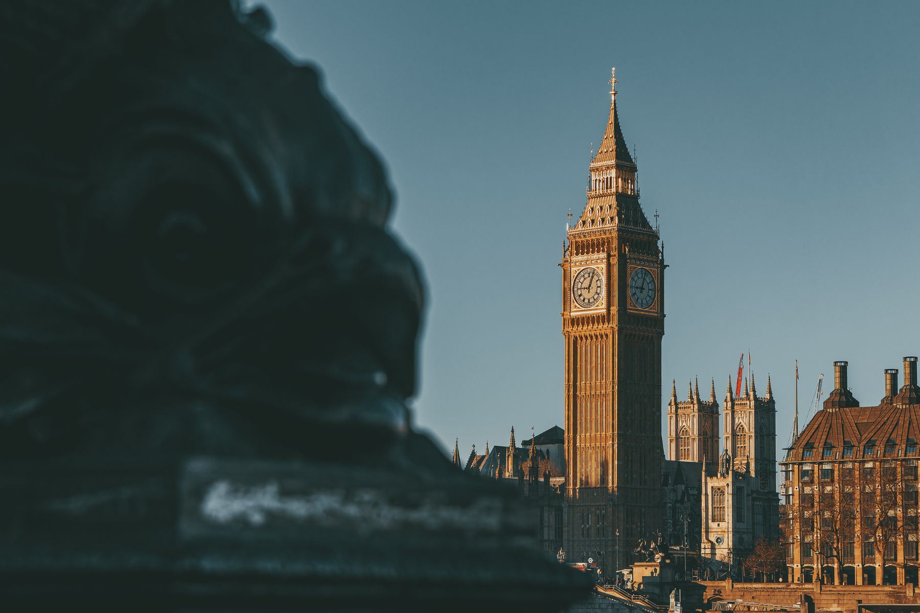 Elizabeth Tower at Westminster, seen past a stone lion on the Embankment